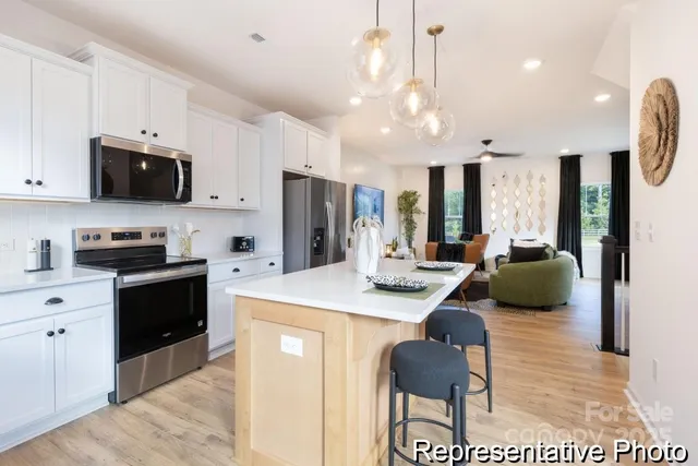 a kitchen with stainless steel appliances kitchen island granite countertop a refrigerator a stove a microwave oven a sink with a dining table and chairs