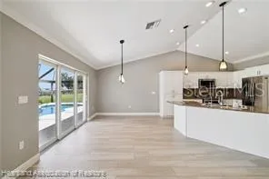 a kitchen with stainless steel appliances granite countertop a refrigerator a sink and a wooden floor