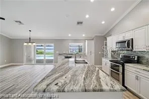 a open kitchen with granite countertop a stove top oven a sink a counter space and cabinets