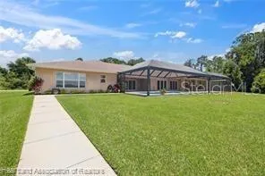 a view of house with a big yard and large trees