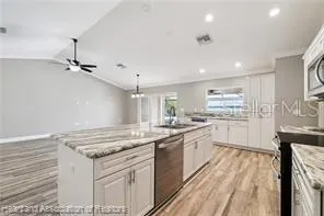 a kitchen with granite countertop white cabinets and black appliances