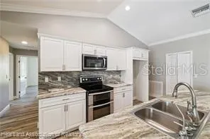 a kitchen with stainless steel appliances granite countertop a stove a sink and a refrigerator