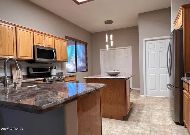 a kitchen with granite countertop a stove a sink and a microwave