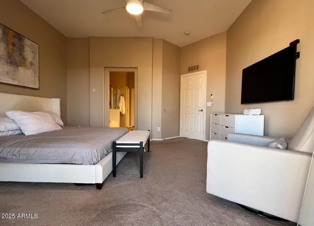 a spacious bedroom with a bed and a flat screen tv