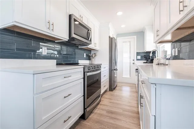 a kitchen with stainless steel appliances granite countertop a stove top oven a sink dishwasher and a microwave oven with large wooden cabinets