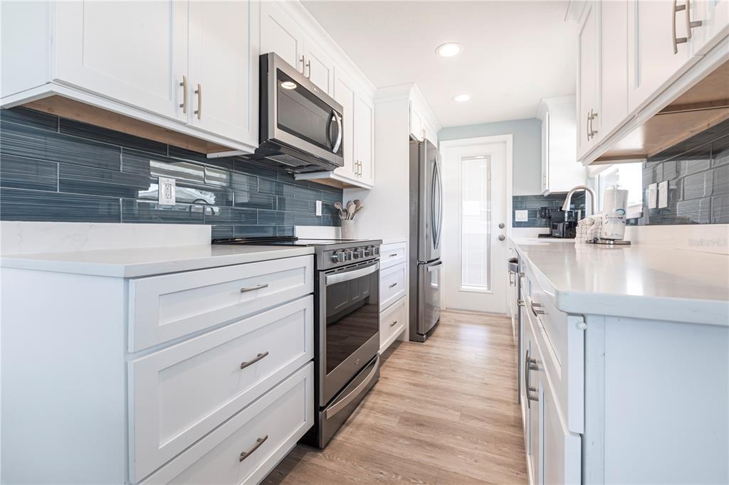 6020 Midnight Pass Road, Unit 53 Sarasota, FL 34242 - Photo 8 of 16 a kitchen with stainless steel appliances granite countertop a stove top oven a sink dishwasher and a microwave oven with large wooden cabinets