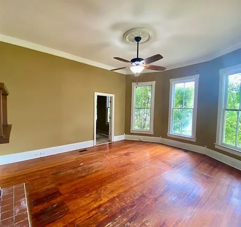 a view of an empty room with wooden floor and a window