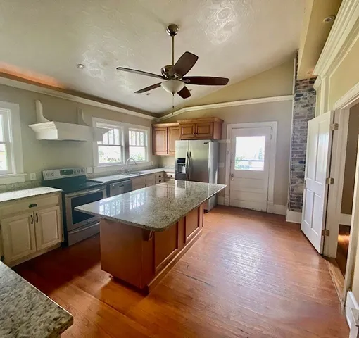 a kitchen with stainless steel appliances granite countertop a refrigerator a sink dishwasher a stove and white countertops with wooden floor