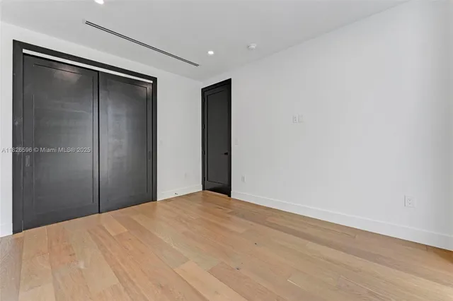 an empty room with wooden floor and closet