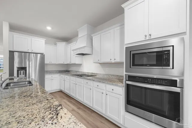 a kitchen with granite countertop a stove microwave and refrigerator