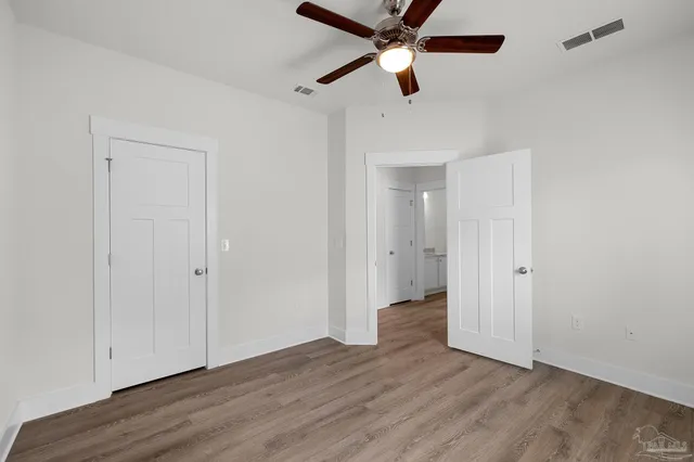 an empty room with wooden floor ceiling fan and windows