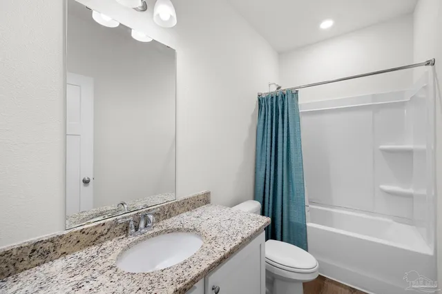 a bathroom with a granite countertop sink a toilet and shower