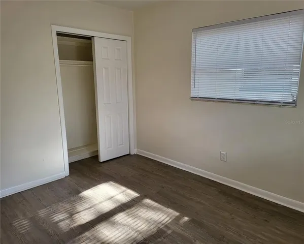 an empty room with wooden floor and closet