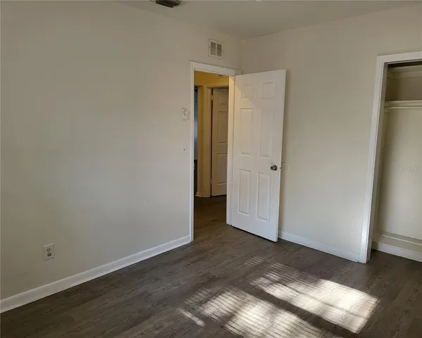 an empty room with wooden floor and closet
