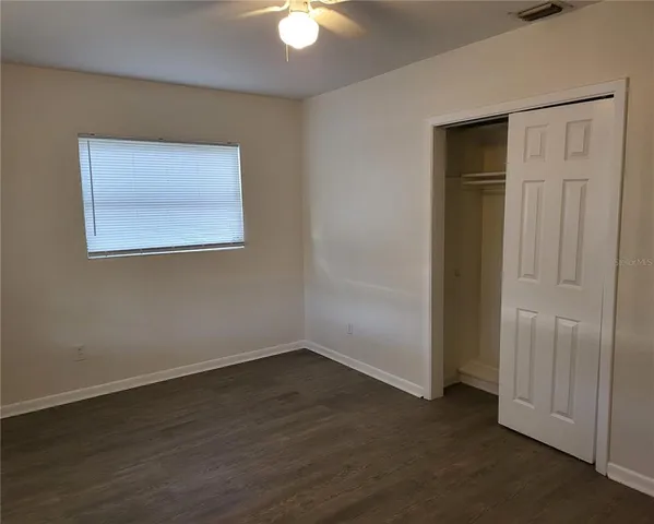 an empty room with wooden floor closet and windows