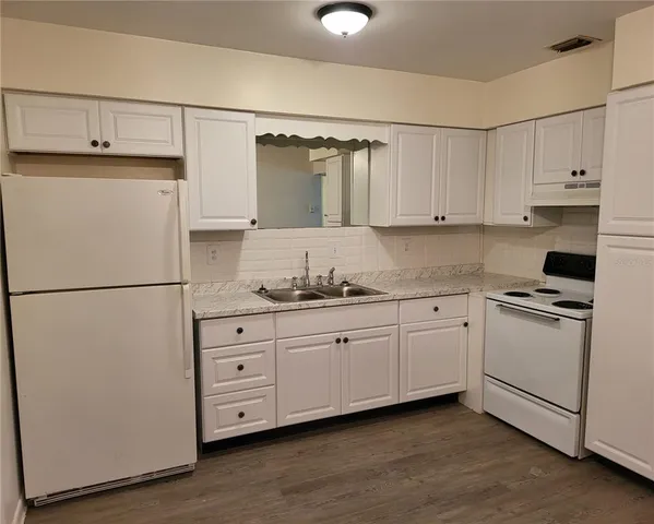 a kitchen with granite countertop cabinets appliances a sink and a window