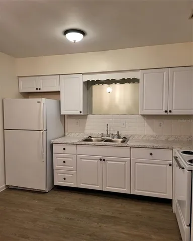 a kitchen with granite countertop white cabinets and white appliances