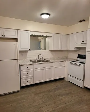 a kitchen with granite countertop white cabinets and white appliances