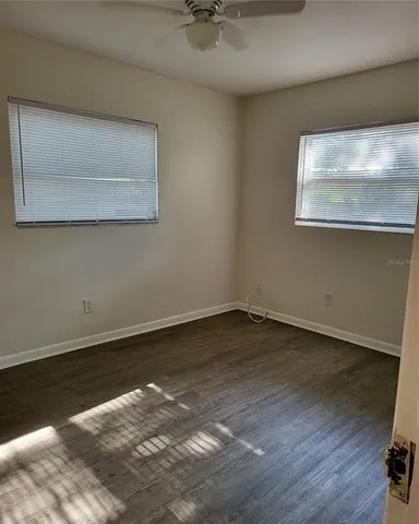 a view of a room with wooden floor and a ceiling fan