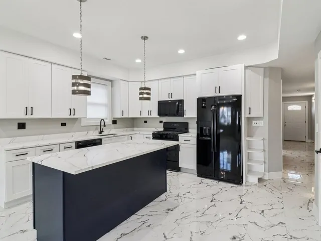 a large kitchen with kitchen island a sink stainless steel appliances and cabinets