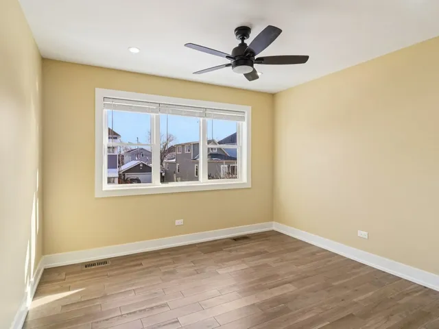 an empty room with wooden floor cabinet and a ceiling fan