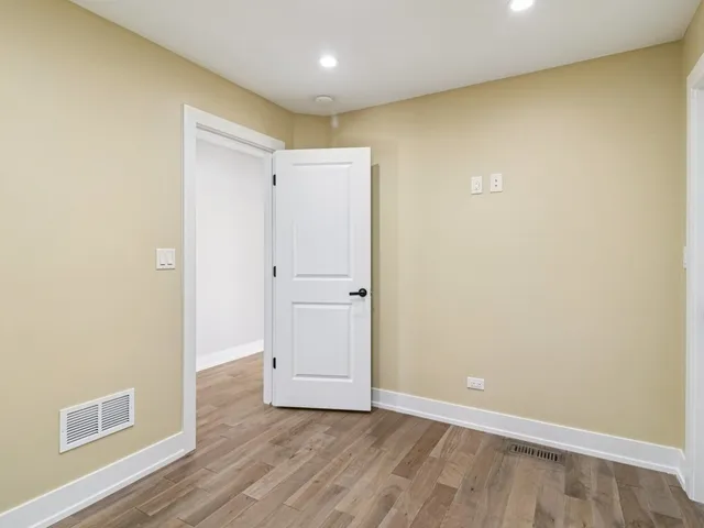 an empty room with wooden floor ceiling fan and window