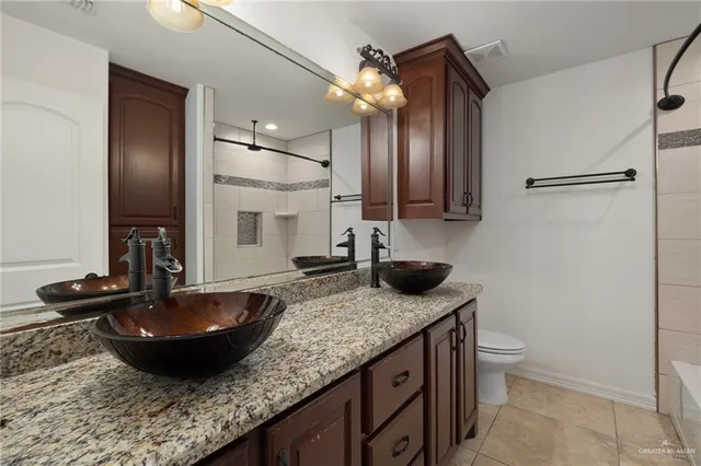 a bathroom with a granite countertop sink a toilet and a mirror