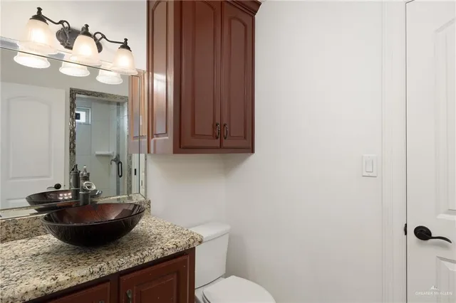 a bathroom with a granite countertop sink a toilet and a mirror