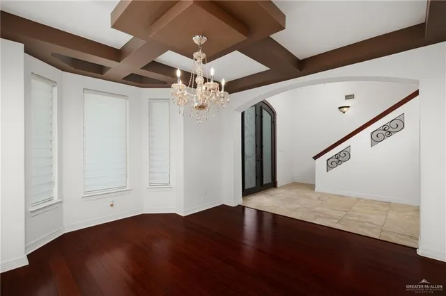 a view of an empty room with wooden floor and a ceiling fan