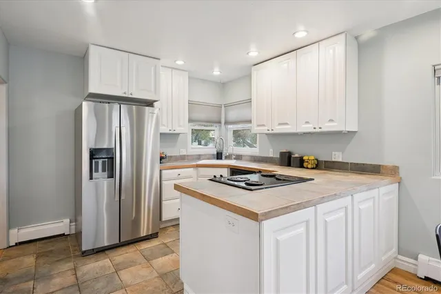a kitchen with stainless steel appliances granite countertop a stove a refrigerator a sink and white cabinets