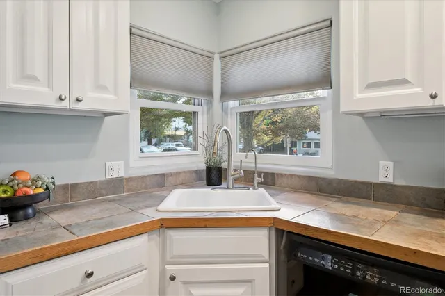 a kitchen with stainless steel appliances granite countertop white cabinets and a window
