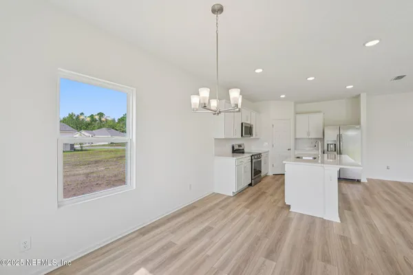 a view of a kitchen with kitchen island white cabinetry and wooden floor
