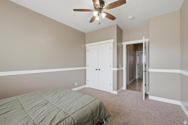 2567 West Rim Rock Drive Stockton, UT 84071 - Photo 29 of 64 Bedroom featuring neutral wall paint with white chair rail molding, a ceiling fan with integrated lighting, carpeted flooring, and a pair of white bifold closet doors