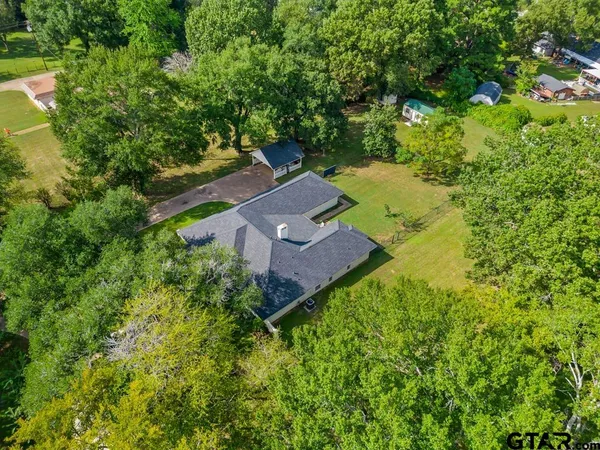 an aerial view of a house with swimming pool and large trees