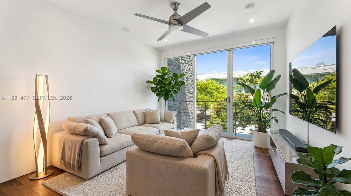 544 Fernwood Road, Unit 544 Key Biscayne, FL 33149 - Photo 9 of 35 Bright second bedroom featuring warm wood floors, ample natural light, and sliding glass doors with lush greenery views, offering a comfortable and versatile space ideal for guests or a home office.