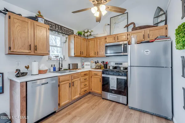a kitchen with stainless steel appliances granite countertop a refrigerator a sink dishwasher a stove and white countertops with wooden floor