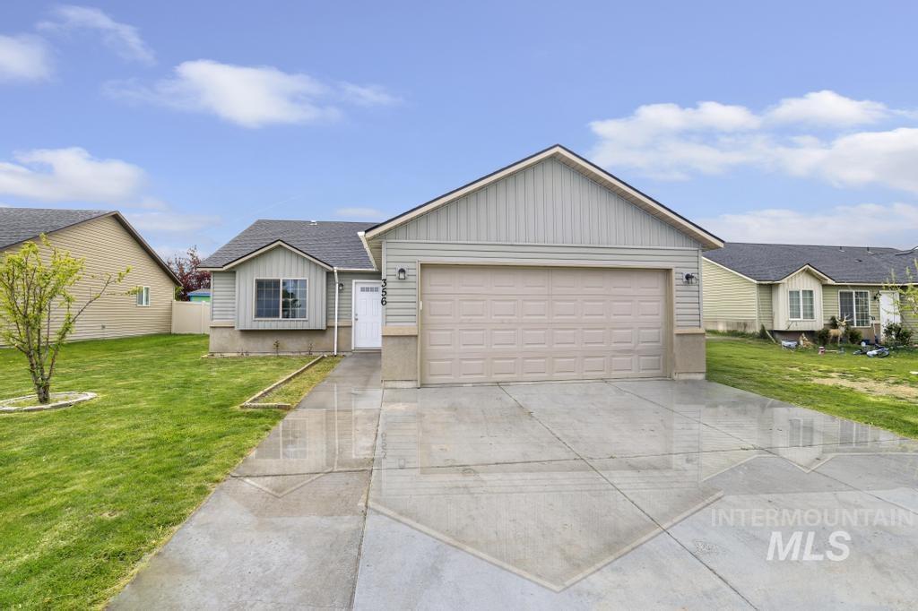 Ranch-style house featuring driveway, a front lawn, board and batten siding, a shingled roof, and a garage