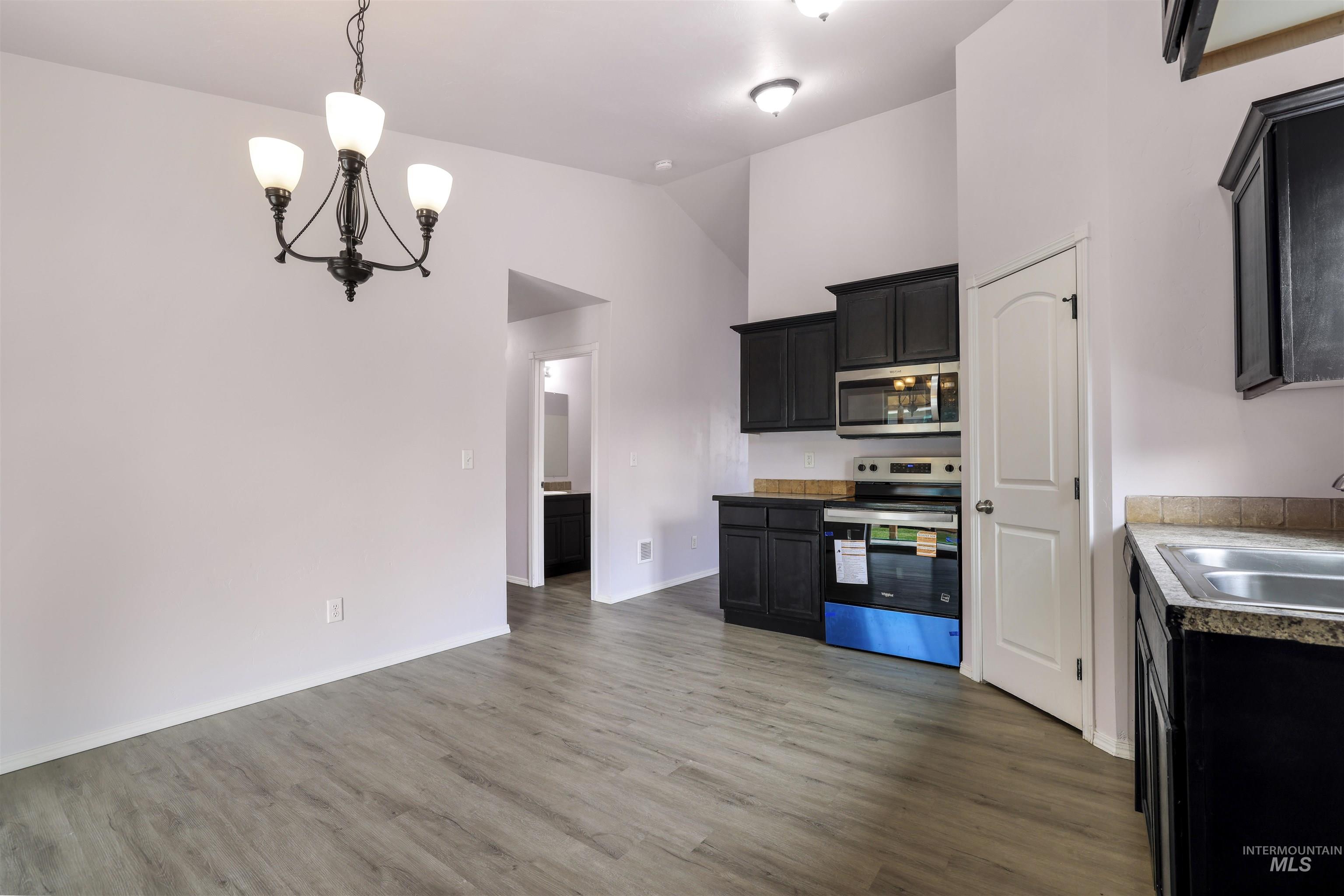 356 Watchmaker Street Twin Falls, ID 83301 - Photo 11 of 22 Kitchen featuring dark cabinets, stainless steel appliances, suspended lighting, dark wood-type flooring, and vaulted ceiling