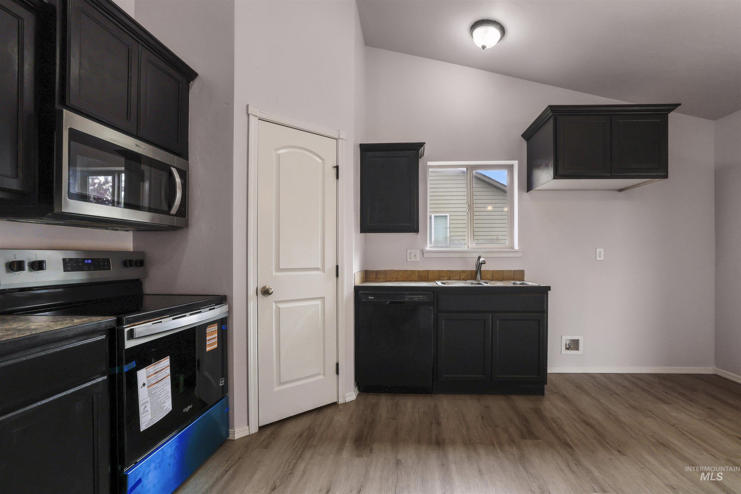 356 Watchmaker Street Twin Falls, ID 83301 - Photo 8 of 22 Kitchen with dark cabinetry, stainless steel appliances, light wood-style flooring, and vaulted ceiling