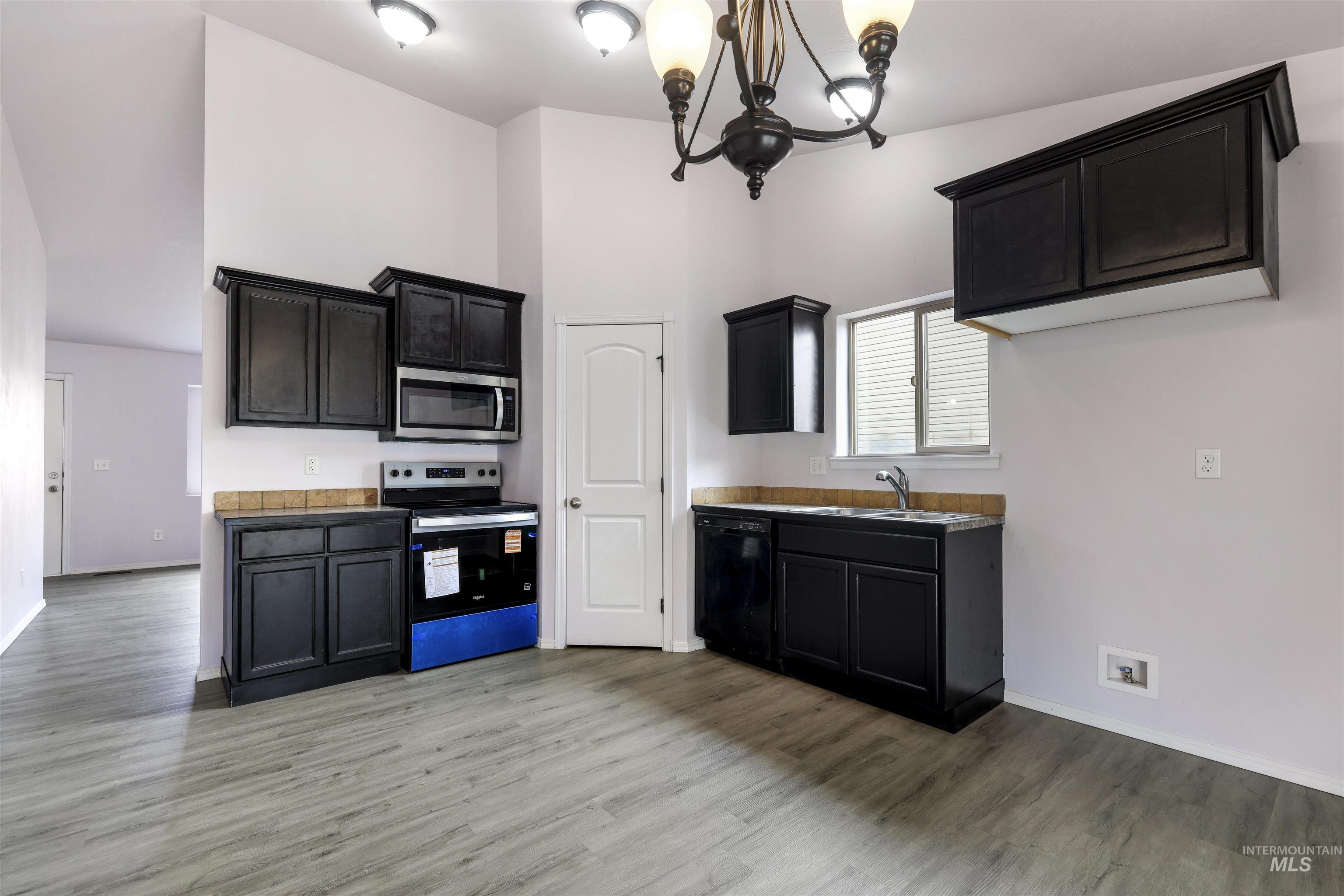 356 Watchmaker Street Twin Falls, ID 83301 - Photo 10 of 22 Kitchen featuring stainless steel appliances, dark cabinets, light wood-style flooring, a chandelier, and a high ceiling