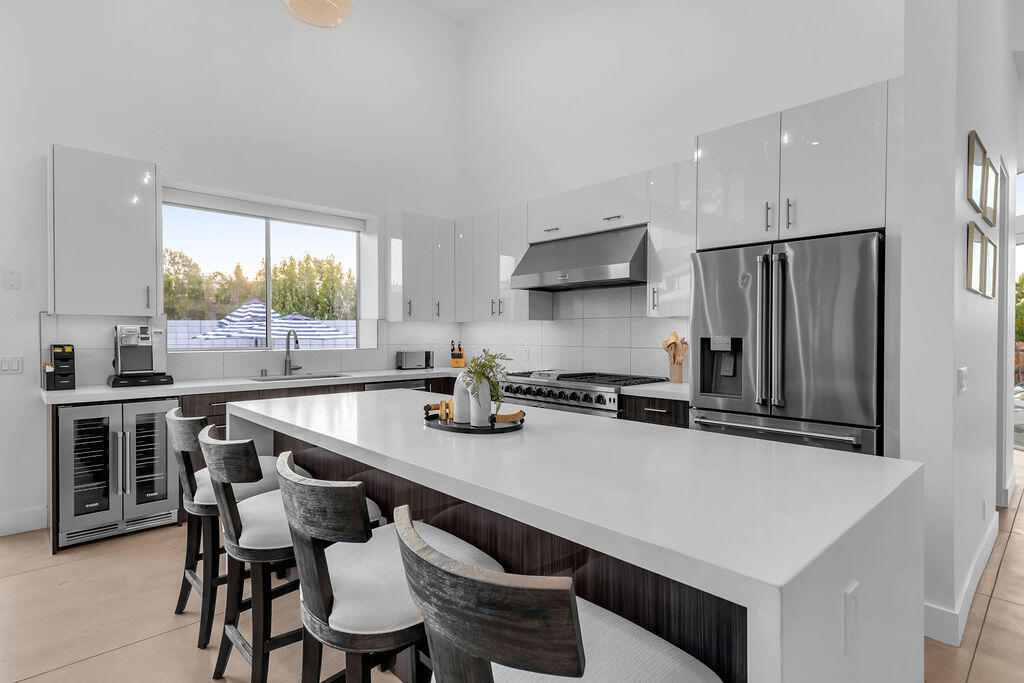 2100 East Sahara Road Palm Springs, CA 92262 - Photo 107 of 117 a kitchen with stainless steel appliances a sink a stove a refrigerator cabinets and a dining table with wooden floor