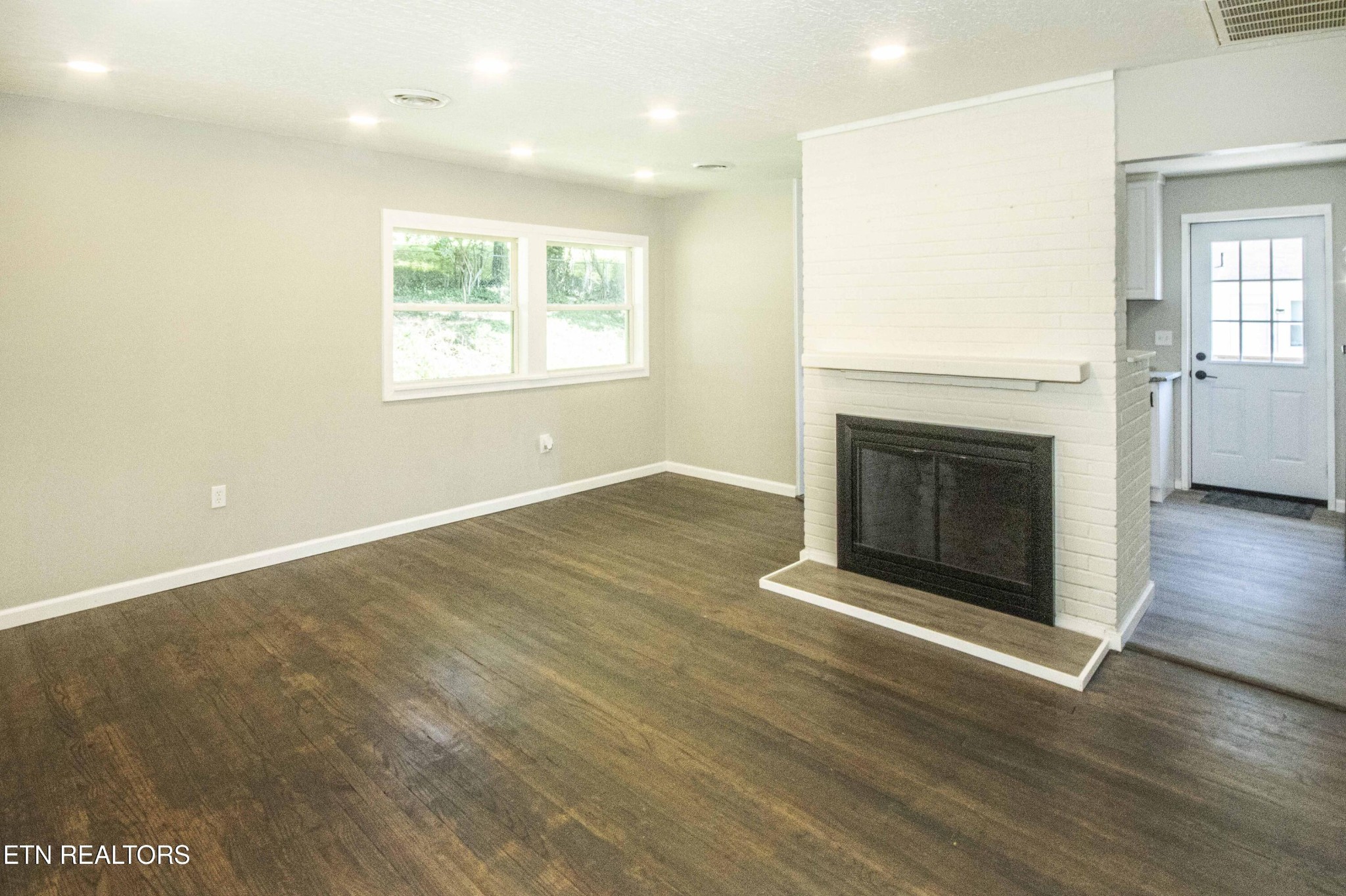 110 Delmar Circle Oak Ridge, TN 37830 - Photo 8 of 38 an empty room with wooden floor a fireplace and windows