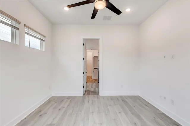 a view of empty room with wooden floor and ceiling fan