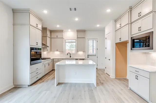 a large white kitchen with stainless steel appliances sink and cabinets