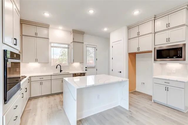 a large kitchen with stainless steel appliances cabinets a wooden floor and a sink