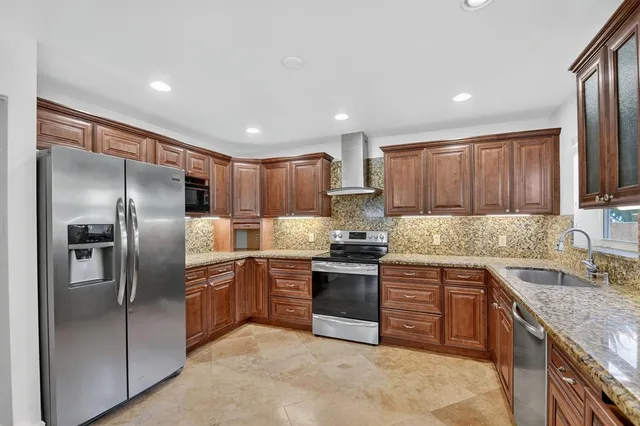 a kitchen with stainless steel appliances granite countertop a sink stove refrigerator and cabinets