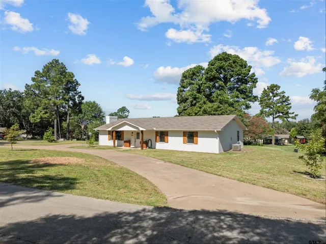 a front view of a house with a garden and trees