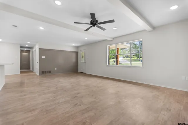 an empty room with ceiling fan and windows