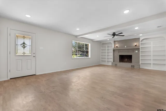 an empty room with windows and fireplace