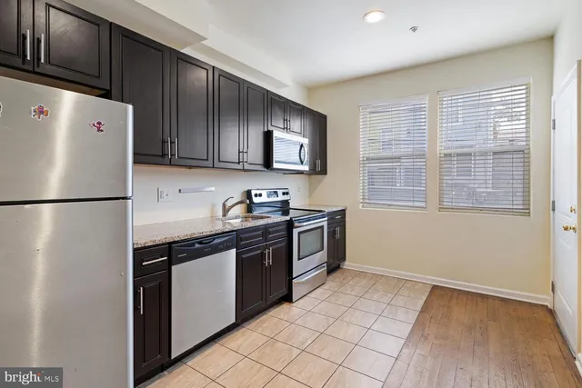 a kitchen with granite countertop a refrigerator and a stove top oven